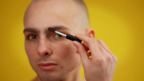 Closeup Face of Confident Male Transgender Applying Mascara Looking at Camera alt
