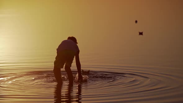 Boy launches Red and green Paper Ships in the river. Origami Paper Boats in kid's hands. alt
