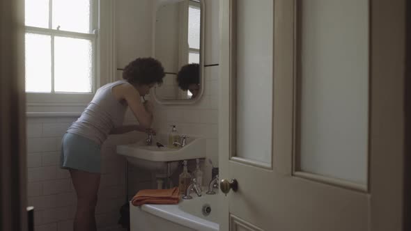 Afro American Woman in bathroom brushing teeth