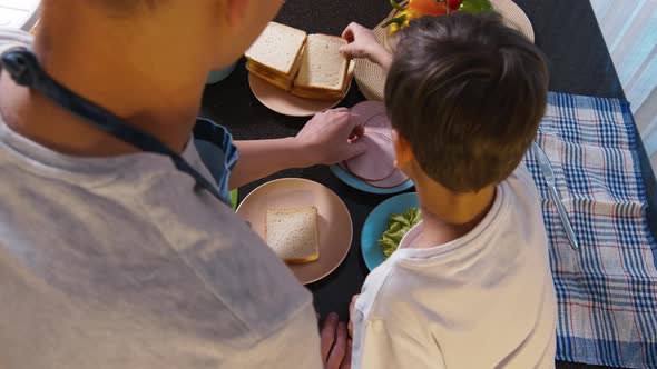 Man and boy taking products and preparing sandwiches together