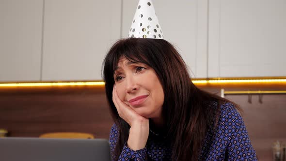 Close Up Upset Aged Woman in Party Hat Celebration Holiday Birthday Alone Home alt