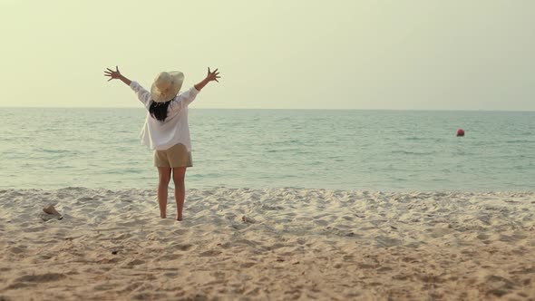 Happy Asian woman running into the beach with arms raised celebrate travel holiday summer.