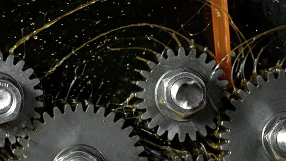 Super Slow Motion Detail Shot of Gear Mechanism and Oil on Dark Background at 1000 Fps. alt