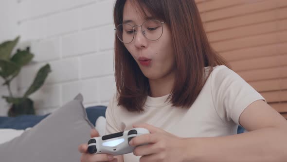Young asian women play video game relaxing in free time sits at home