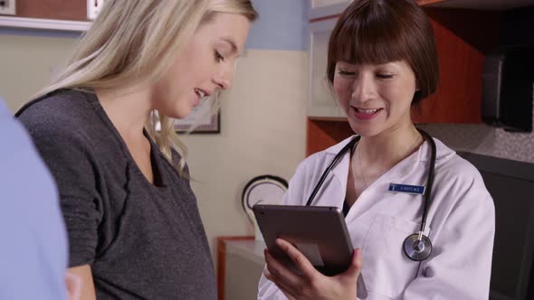 Doctor and pregnant woman look at digital tablet together