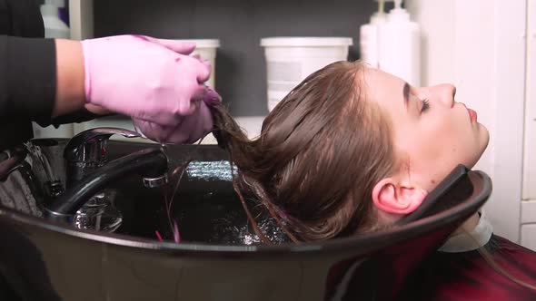 A Hairdresser Applies a Moisturizing Balm to the Wet Hair of a Young Woman