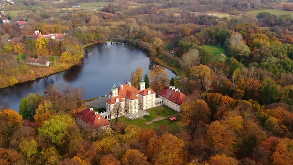Palace by a lake or castle in forest. Autumn colorful woods and big impressive fairy tale building. alt