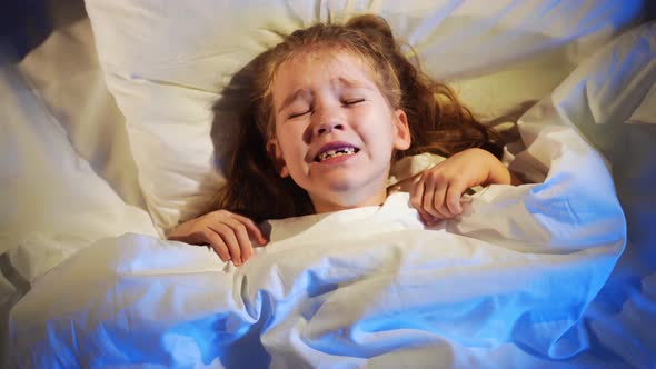 A sweet little girl naps in bed in her room, sees a nightmare and fears in her sleep alt