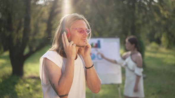 Positive Caucasian Man Listening to Music in Headphones Smiling Standing in Sunrays on the Left with alt