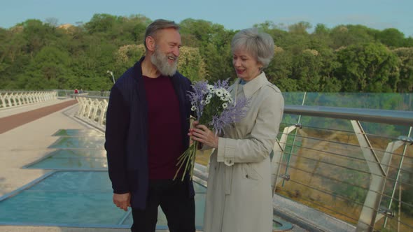 Charming Aged Woman Taking Bouquet Smelling It Expressing Happiness alt
