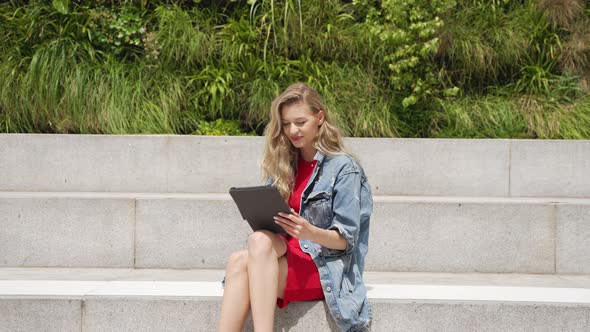 Young Woman Using Tablet While Sitting on Street