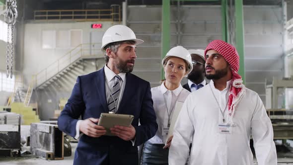 Caucasian engineers welcoming international colleagues at factory