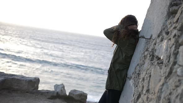 Slow motion of a girl looking at the beach with hair flying with the wind alt