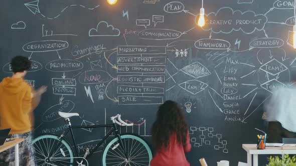 Time Lapse of Creative Youth Coworkers Writing and Drawing on Black Chalkboard Indoors alt