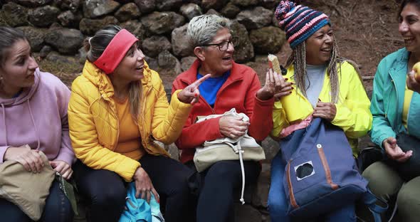 Multiracial women eating a snack during trekking day alt