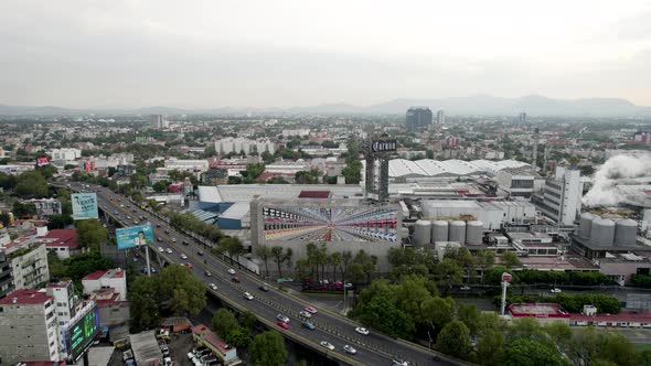 backwards drone shot of beer factory and morning commute and car traffic mexico city alt