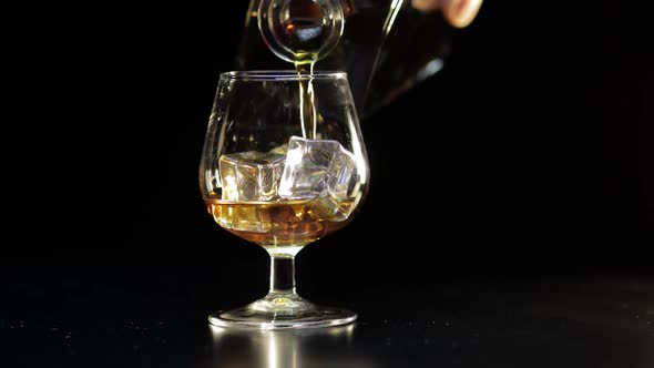Pouring Whiskey, Cognac Into Glass. Black Background. Pour of Alcohol Drink alt