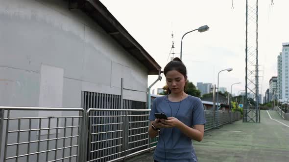 Asian female athletes walking using smartphones typing sending message social media after running.