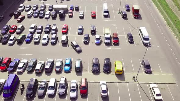 A bird's-eye view of parked cars in the parking lot near the shopping center. alt
