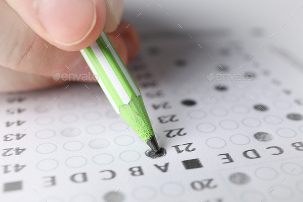 Student fills answers test sheet, close up