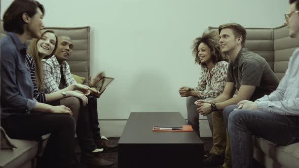 Men and women sitting together and having discussion with digital tablet in office