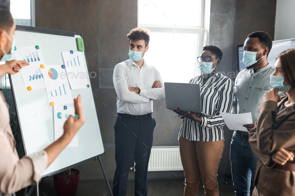 Employee in protective mask presenting business strategy on whiteboard