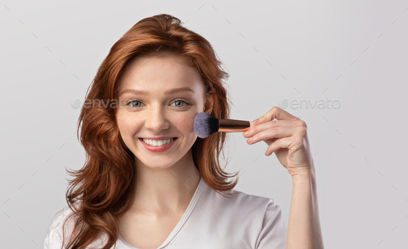 Ginger-Haired Young Lady Posing Holding Cosmetic Brush In Studio