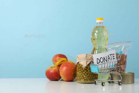 Shop trolley with text Donate and different food against blue background