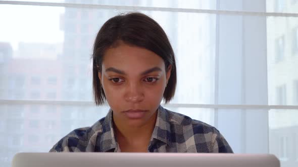 A Black Woman Sitting at Home Looking at a Laptop Monitor