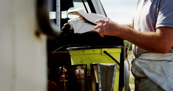 Beekeeper keeping workwear in container on truck alt
