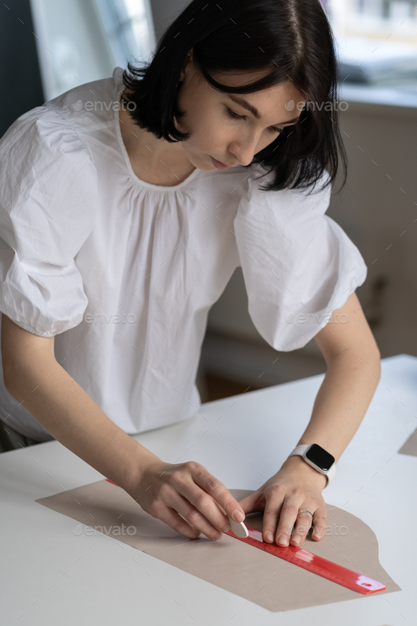 Tailor couturier measuring cloth. Closeup of sewer woman hands hold ruler  to cut material for sewing Stock Photo by varyapigu