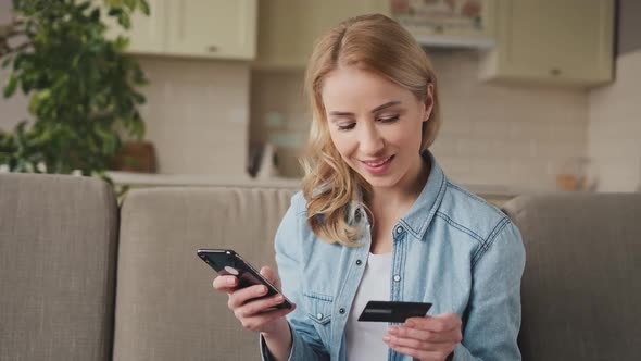 Woman 30s Makes Online Purchases in Smartphone with Bank Card at Home alt