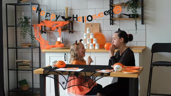 Little Girl with Mom Inflates Halloween Balloons alt