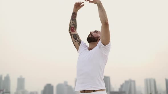 Male Yogini Extending His Arms High As He Stretches In An Up And Down Motion alt