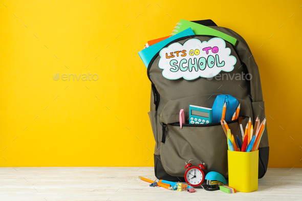 Text Let\'s go to school and school supplies on yellow background