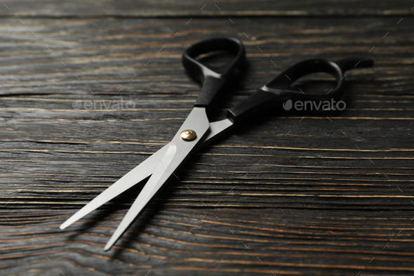 Black hairdresser scissors on wooden background, close up Stock