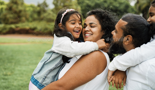 Happy indian family having fun outdoor - Hindu parents laughing with their children at city park - Stock Photo - Images