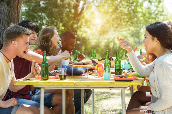 Happy multiracial friends doing picnic outdoor - Stock Photo - Images