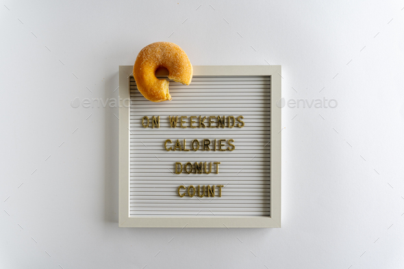 Letterboard With Words That Spell On Weekends Calories Donut Count, in golden letters, with a donut