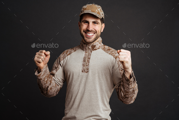 Excited masculine military man smiling and making winner gesture