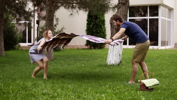 Father and Mother are Preparing Picnic Cover Laying It on Grass alt