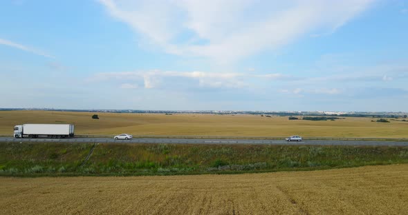 Traffic On The Highway In The Countryside Between Wheat Fields