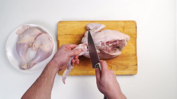 Male Hands Butcher Carcass of Raw Chicken on a Wooden Cutting Board alt