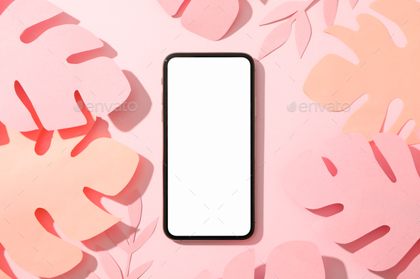 Phone with empty screen and decorative palm leaves on pink background,top view