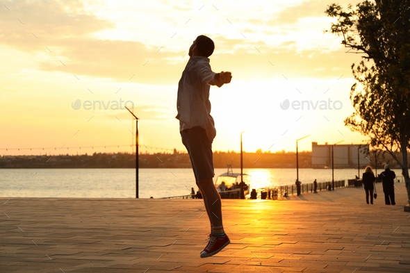 Photo of a young man in a jump. Happy man. Amazing sunset