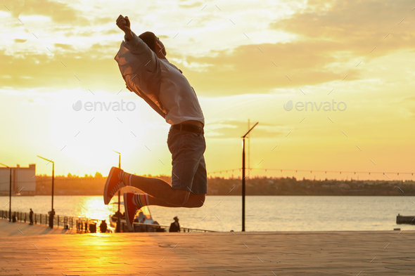 Photo of a young man in a jump. Happy man. Amazing sunset