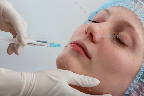Beauty specialist filling lips of woman with by liquid in close up
