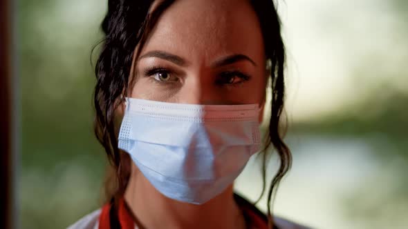Close Face View of Young Female Doctor or Nurse Wearing Surgical Mask and Looking at Camera alt