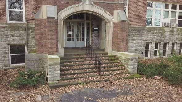 Smooth pan of outdoor historic brick building and entryway on autumn day. alt
