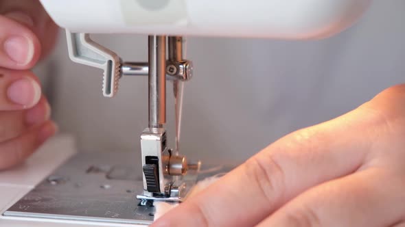 A Woman is Sewing the Hem of Curtains the Edge of a Pillowcase Clothes Sheets on Sewing Machine